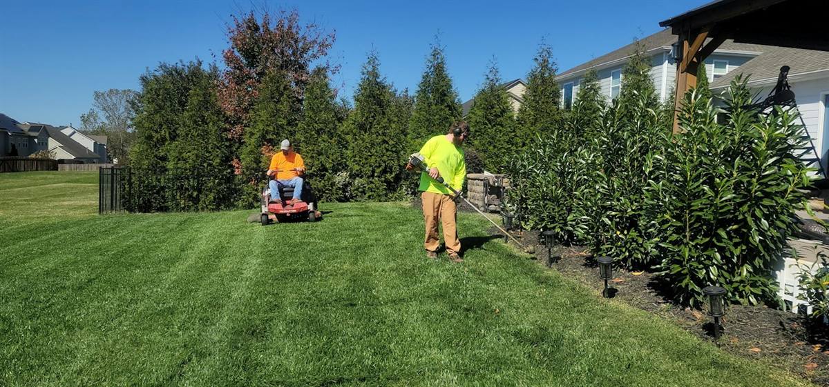Grounds crew cutting and trimming a commercial lawn