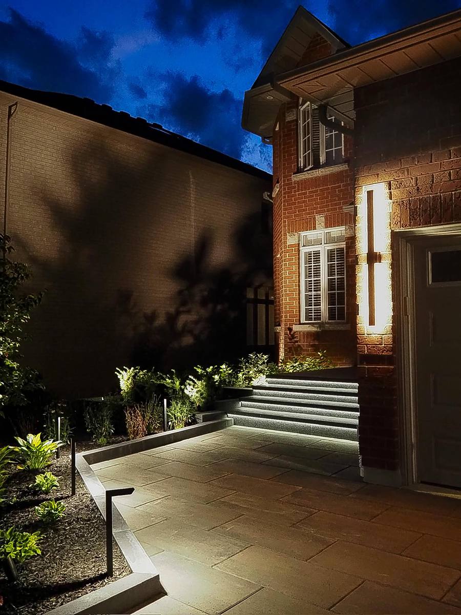 Front entrance with lit steps and garden at night