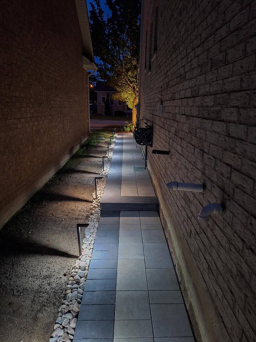 Side yard slab walkway lit at night